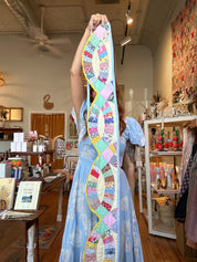 Person holding a colorful quilt bunting in a store setting
