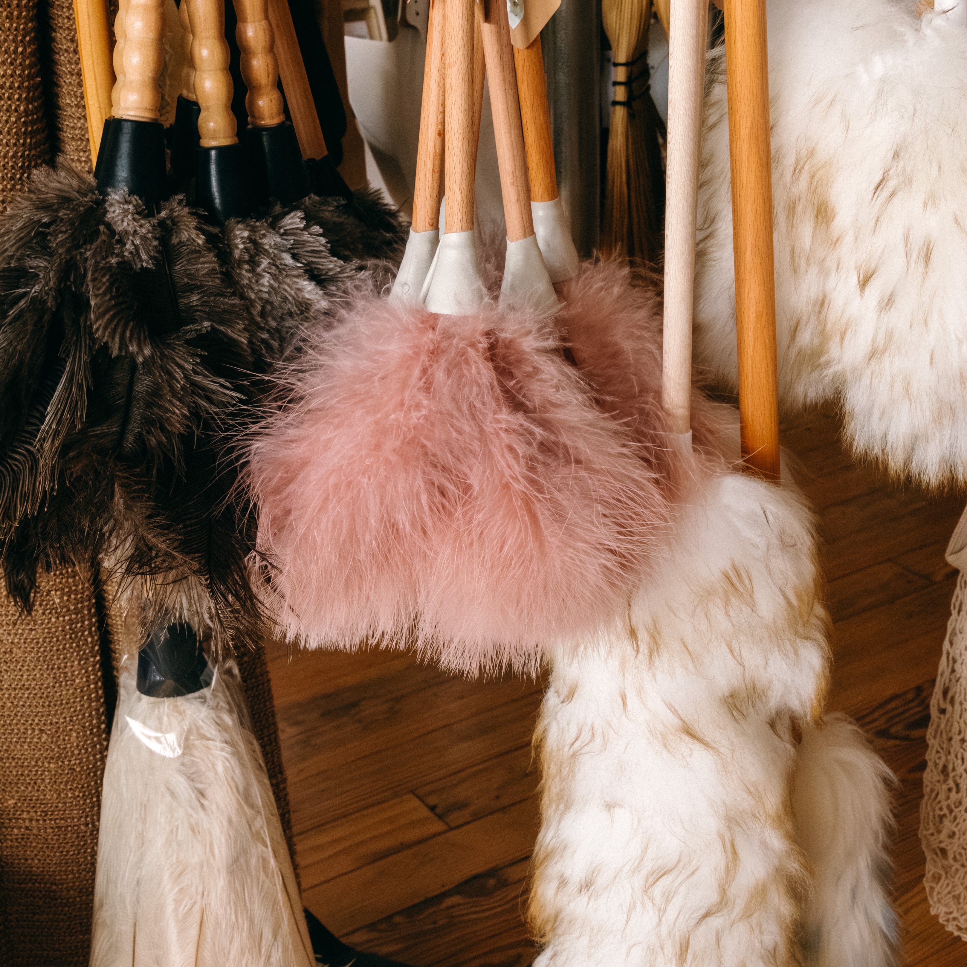 Collection of feather dusters and wool dusters cleaning products hanging above a wooden floor background.

Description: Categories image promoting Brushes & Cleaning goods on the Springfield Mercantile Co. homepage. 
Keywords: Springfield Mercantile Co., brushes and cleaning, categories section, online shop, Shopify
