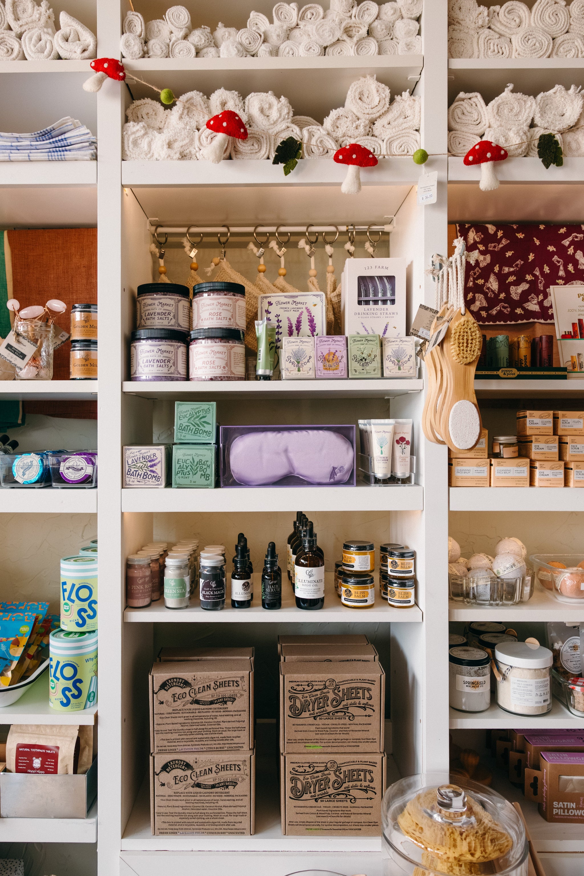 Bright and cheerful shelving unit with various eco-friendly cleaning and self care goods including soaps, bath bombs and bath salts.