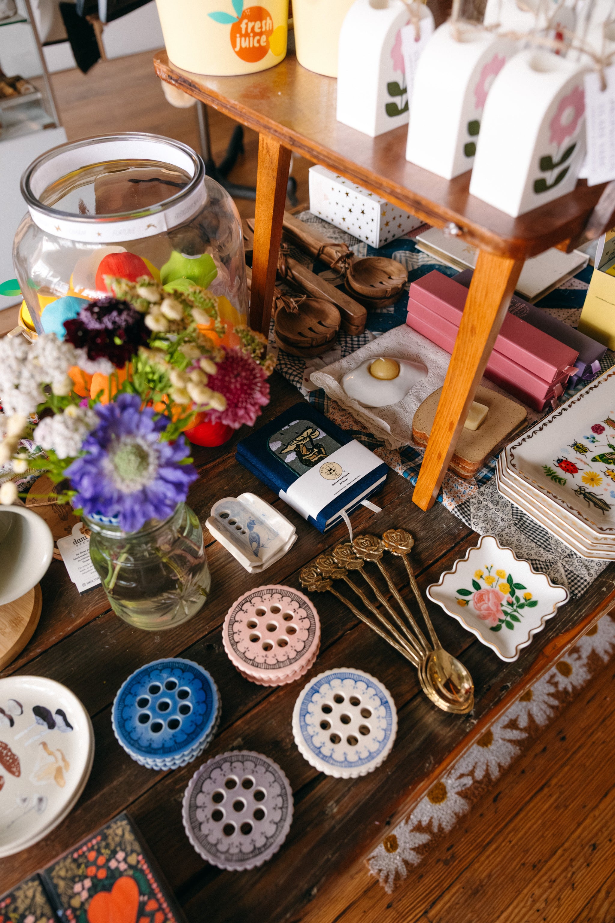 Vintage table with decorative items including unique bud vases, candles, and patterned flower frog jar toppers.

Description: Sliding image card promoting Stylish Home goods on the Springfield Mercantile Co. homepage. 
Keywords: Springfield Mercantile Co., home decor, stylish home, sliding image card, online boutique, Shopify
