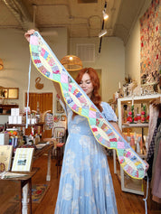 Woman holding a long, colorful quilt in a store setting