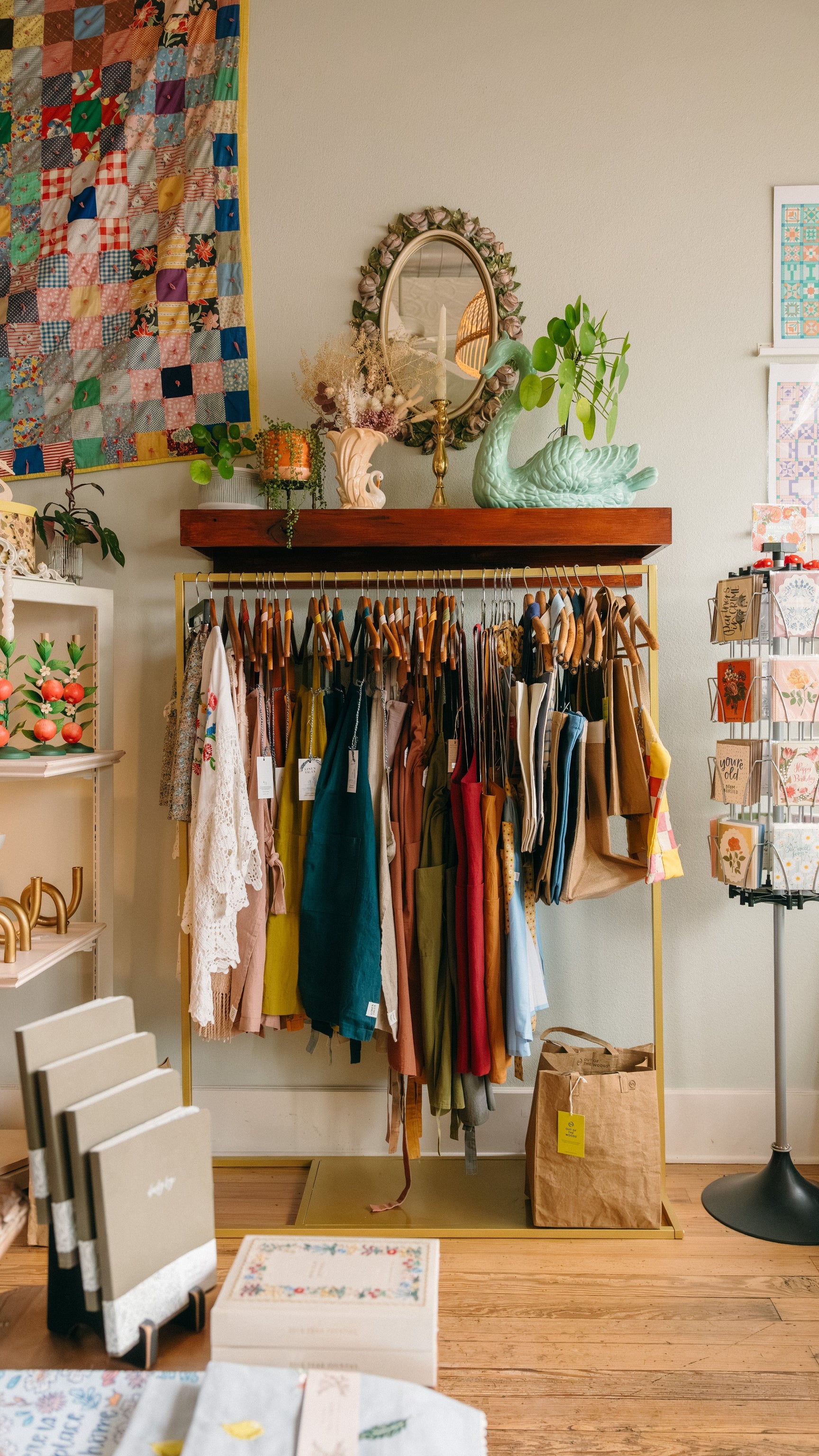 Clothing rack with a variety of colored aprons and tote bags in a home goods store setting. Shelf displays in the background show unique candles and candle holders.
 
Description: Banner image promoting Unique Home Goods on the Springfield Mercantile Co. homepage. 