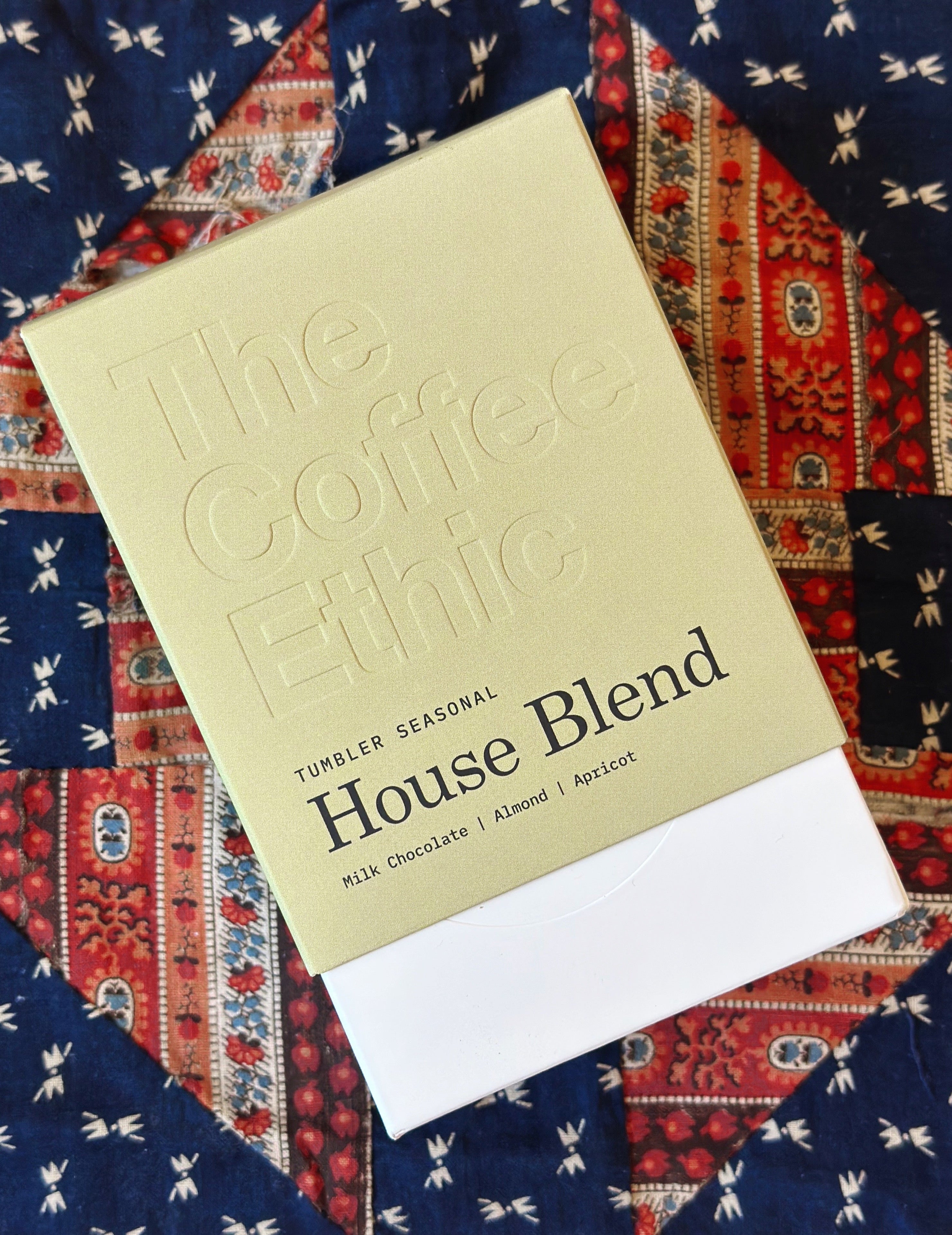 The Coffee Ethic tumbler packaging on a patterned fabric background